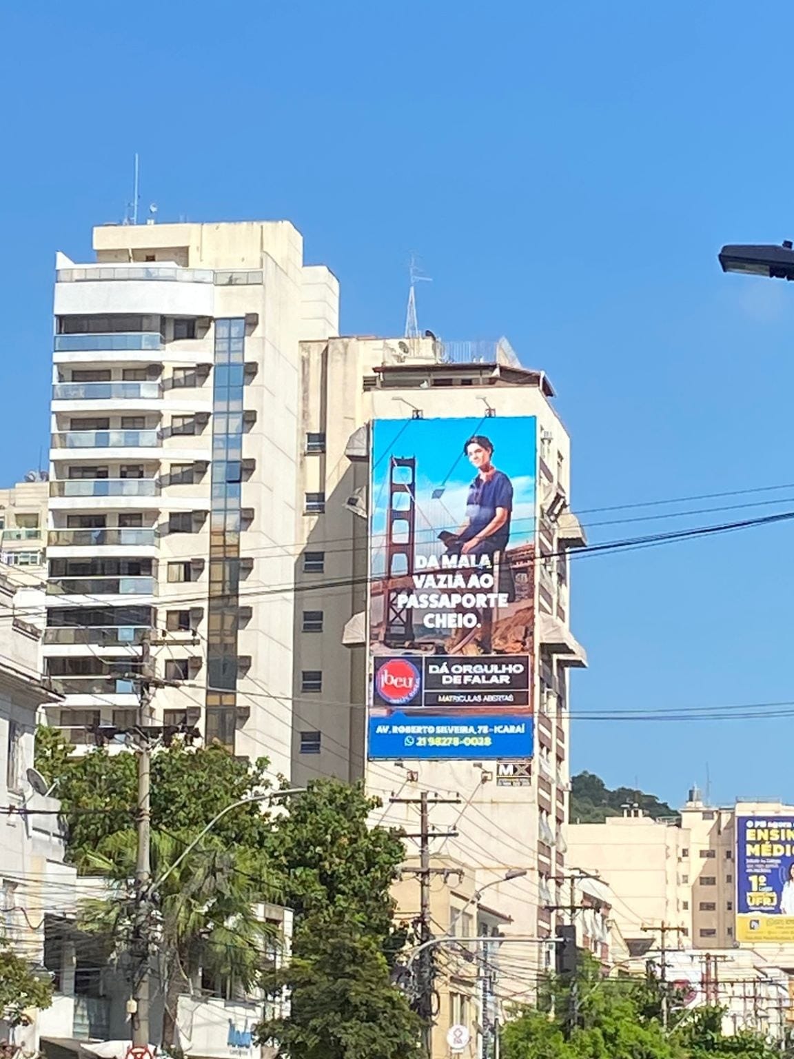 Empena vertical do Ibeu na lateral de um prédio, com a frase Da mala vazia ao passaporte cheio