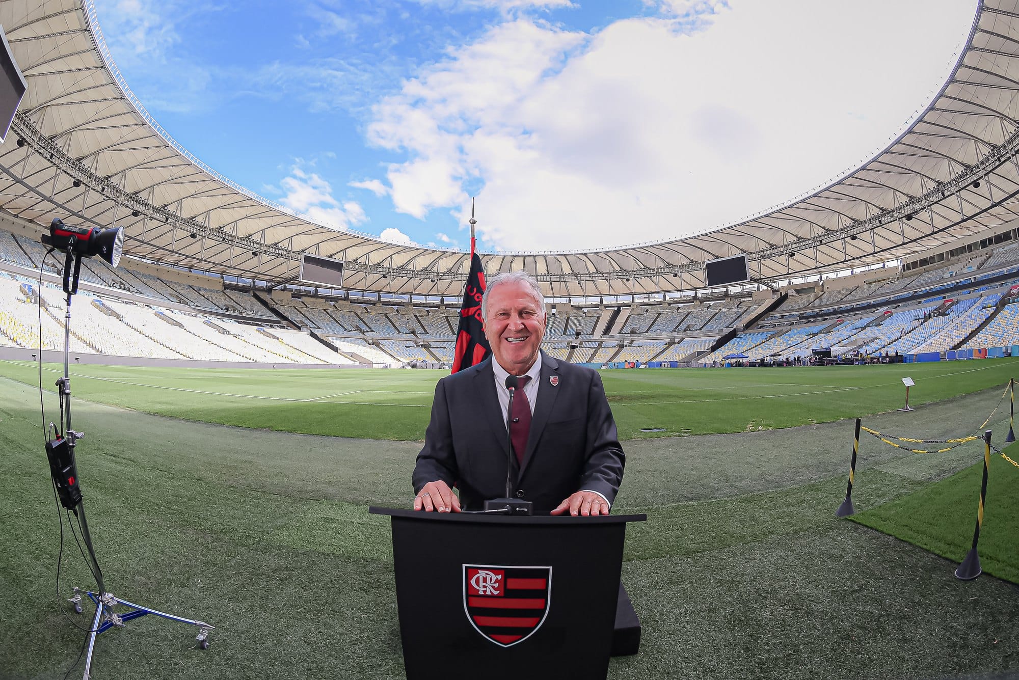 Zico no púlpito no gramado do Maracanã, com a arquibancada vazia e o céu ao fundo