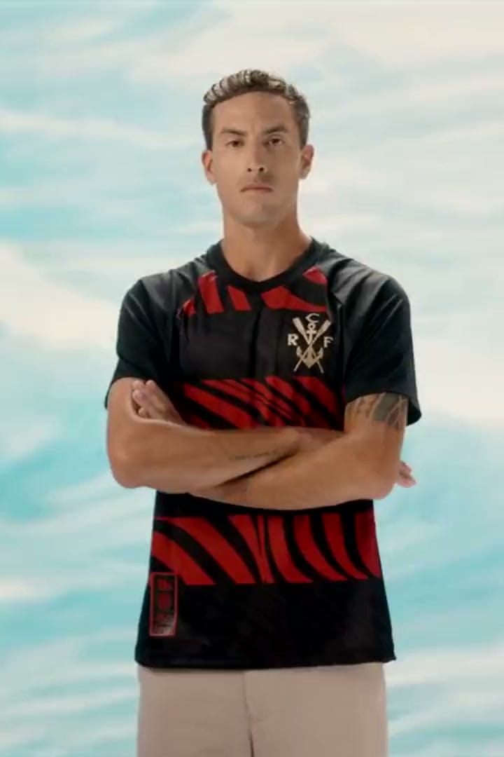 Jogador com a camisa Pherusa, listras vermelhas e pretas e o brasão dos remos, diante de um mar em aquarela